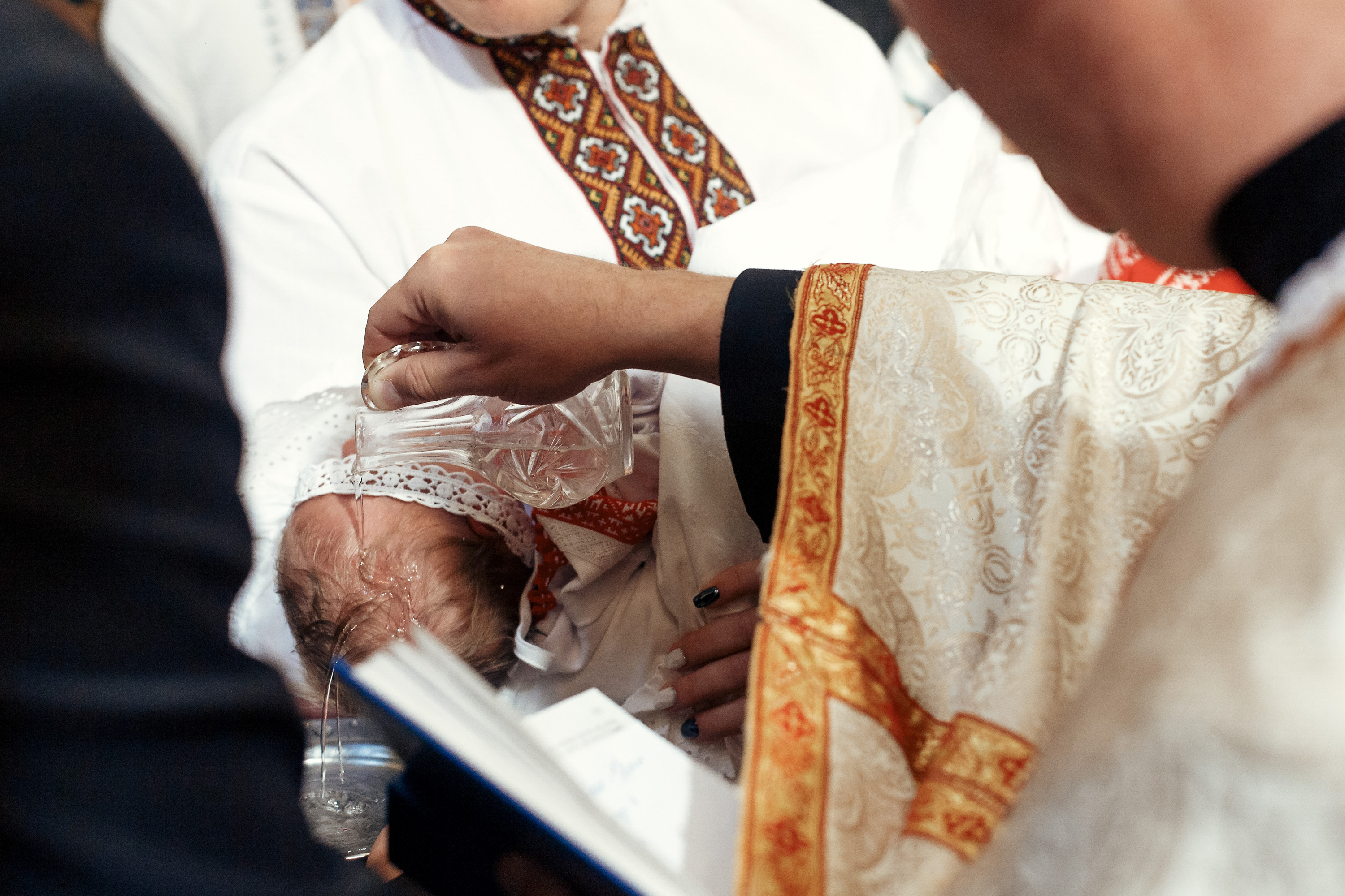 Baby being baptized - priest pouring water over the head of the baby