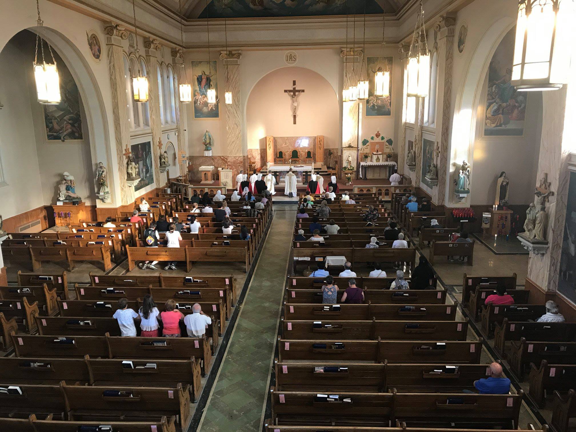 photo of st. anns during adoation taken from the choir loft. Father and other clergy kneeling at the front with a busy church of people kneeling